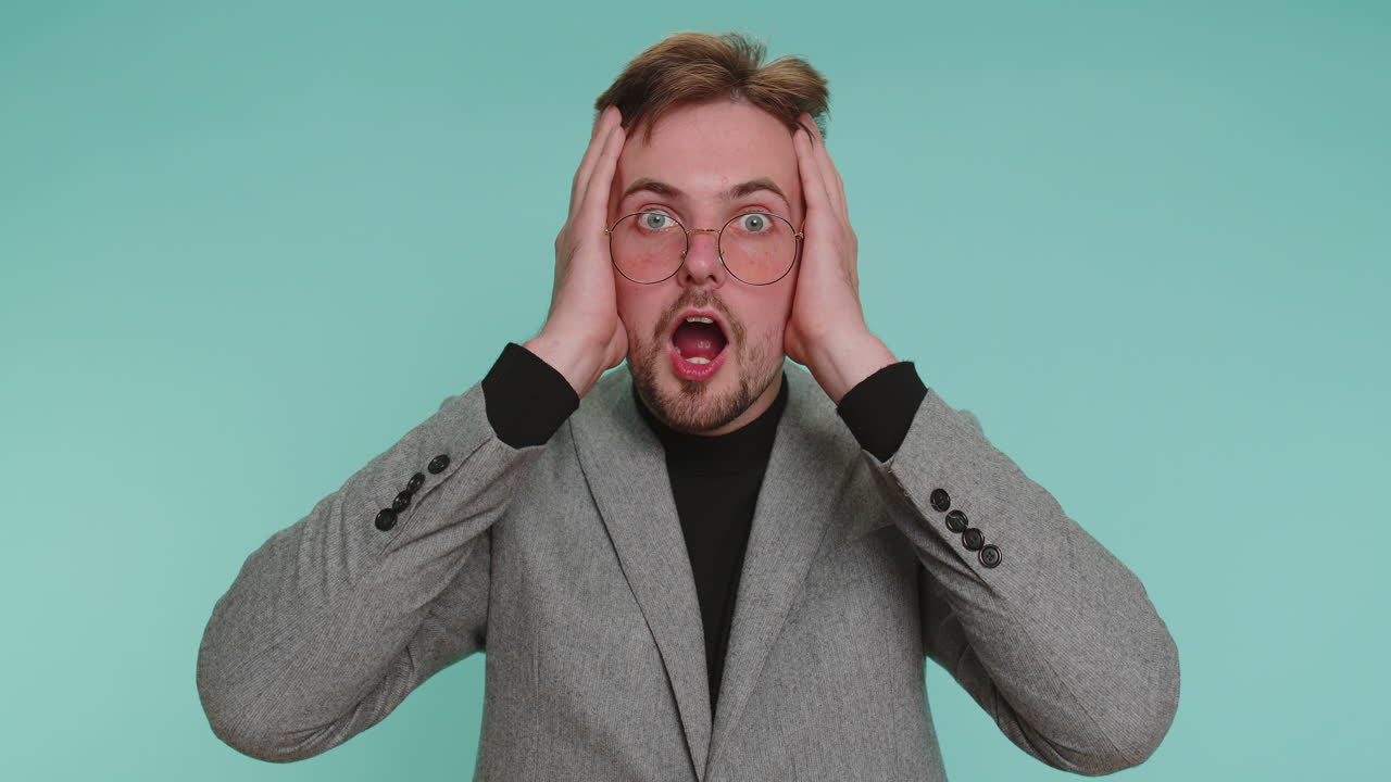 놀라서 흥분한 남자가 커다란 눈으로 카메라를 쳐다보며 놀랐습니다. 갑작스러운 승리에 충격을 받았습니다.