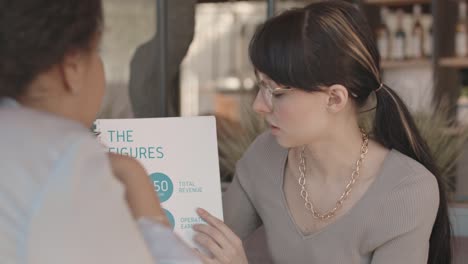 two businesswomen discussing financial issues in cafe