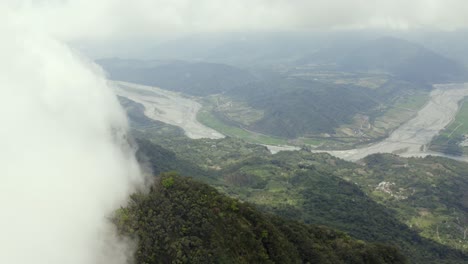 high altitude aerial view above dulan mountain peak over clouds to vast cultivated farmland below in taitung valley