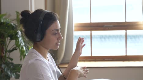 young indian woman works online conference call, training with people, uses laptop computer. bright room at home