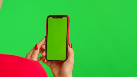 woman holding a red smartphone with green screen