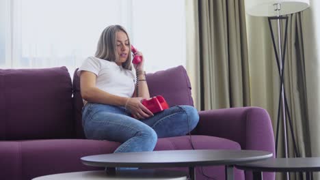 woman sitting on couch talking on a rotary phone