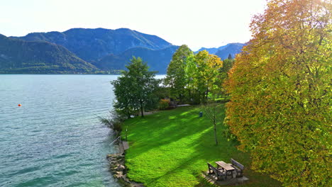 Drone-rises-from-picnic-table-by-Lake-Attersee-to-overlook-coastline-in-Austria