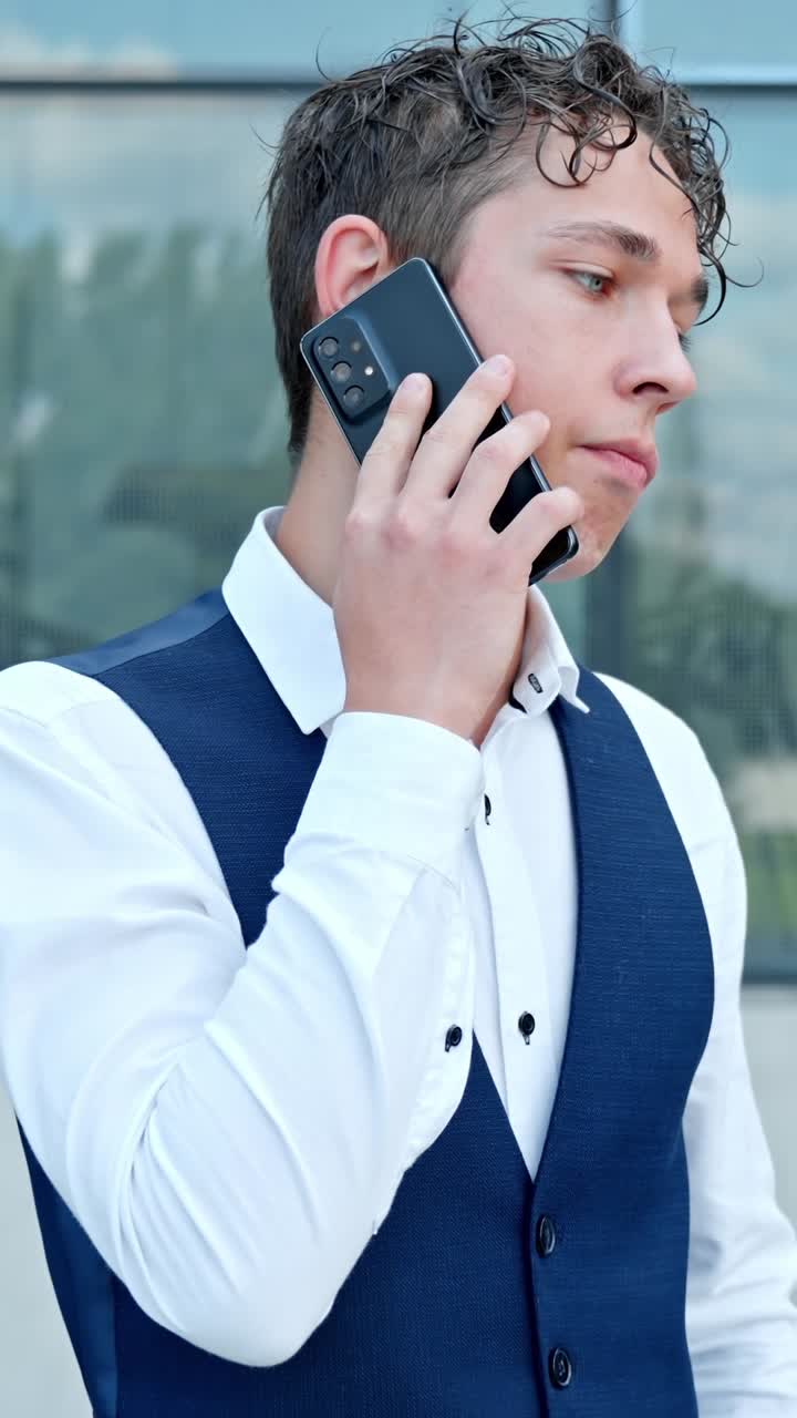 Young Businessman Talking On His Phone Outdoors - Vertical Shot