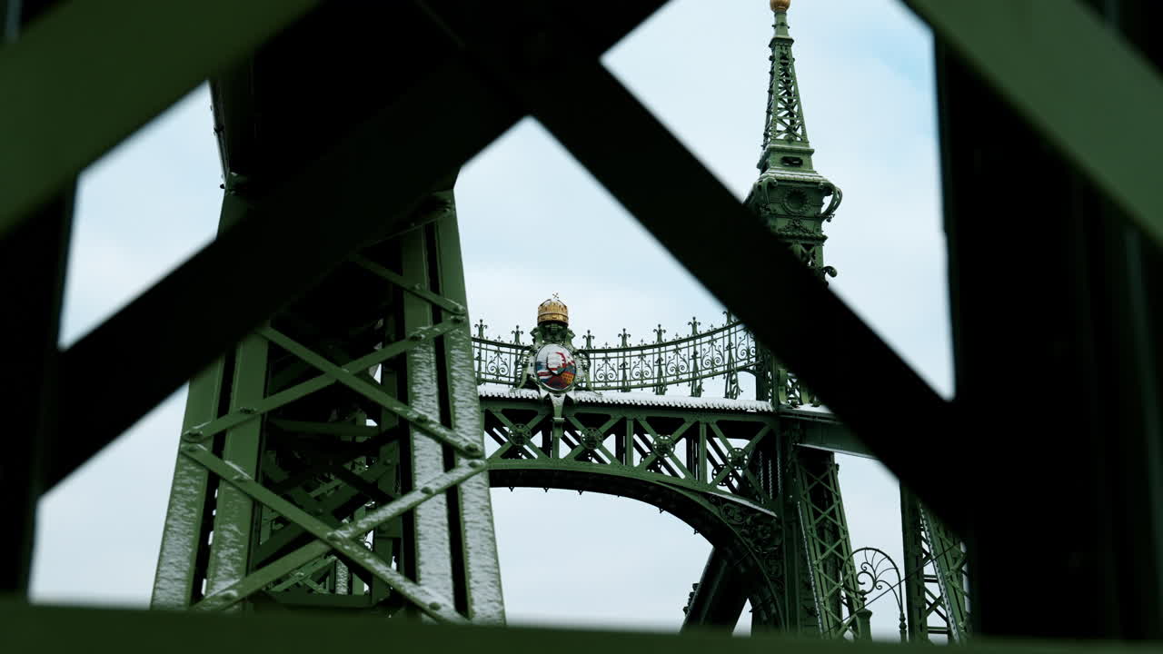 Cận cảnh kiến trúc Cầu Liberty ở Budapest, Hungary, được đóng khung qua các dầm thép xanh, làm nổi bật thiết kế lịch sử, cấu trúc và kỹ thuật đô thị mang tính biểu tượng