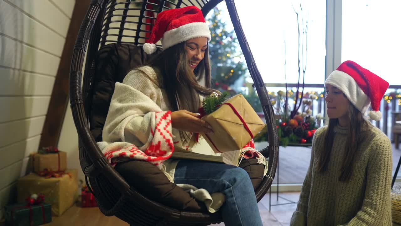 dos amigos intercambiando regalos de navidad en una silla colgante
