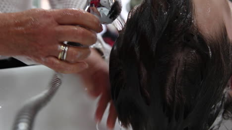 primer plano de las manos de un peluquero lavando el cabello de un cliente antes de cortarse el pelo
