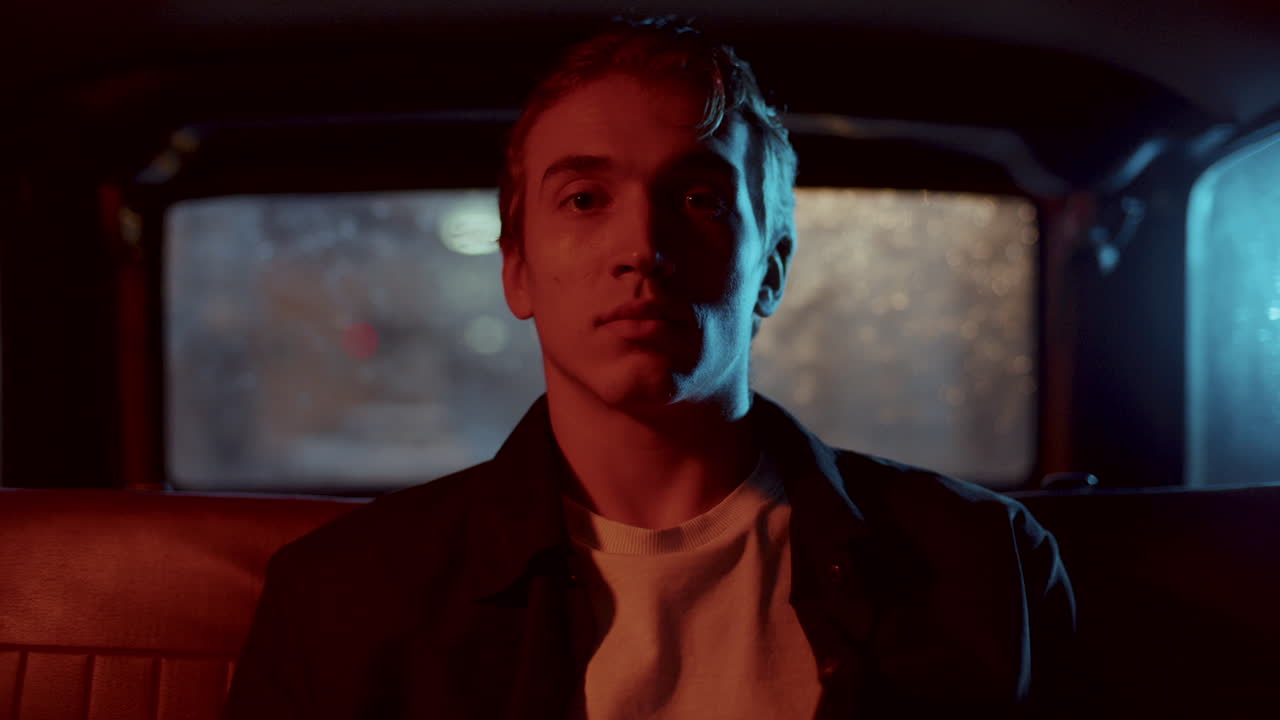 Portrait of Young Man Sitting in Car Backseat on Rainy Night