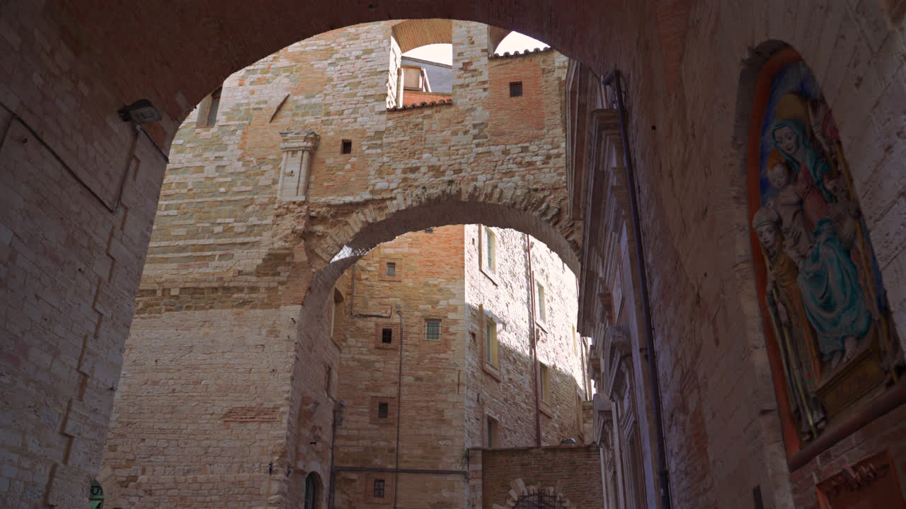 Arched stone walkway in old Perugia with sunlight filtering through walls