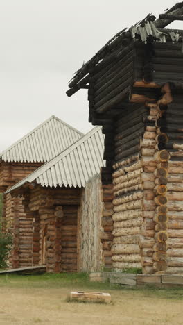 antigua casa de madera con techo quemado por el fuego en un día nublado de verano. asentamiento medieval con edificios de madera cerca de abedul. objetos arquitectónicos antiguos