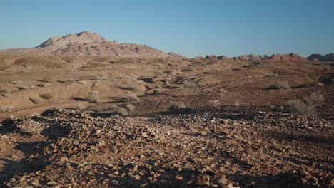 a wide, moving angle of desert rocks in the foreground with a mountain range juxtaposed to a clear blue sky