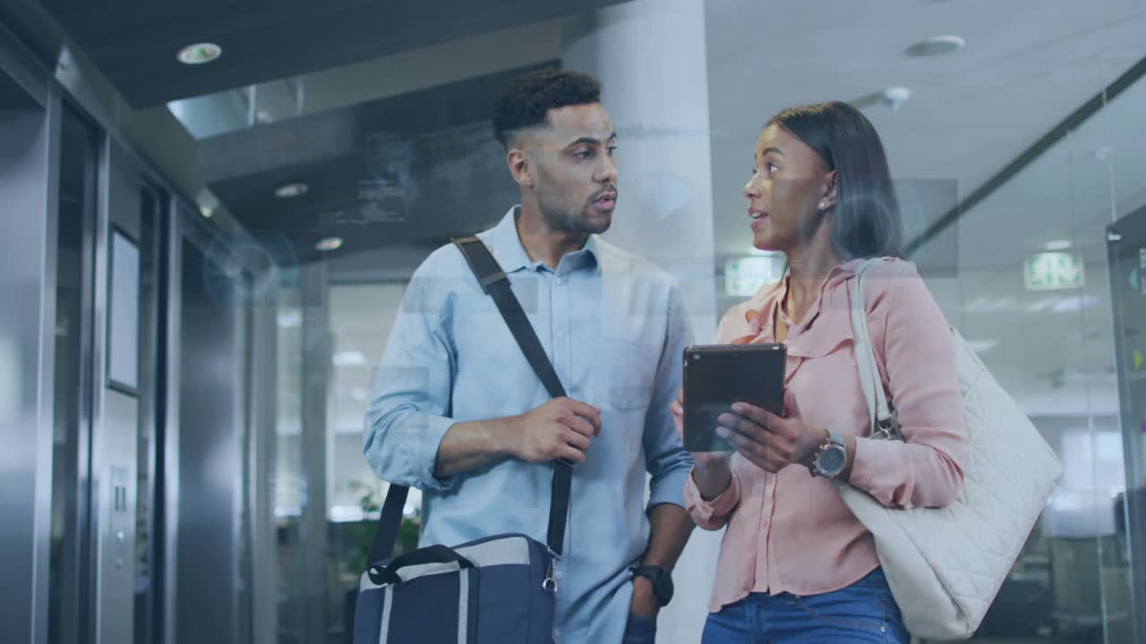 Woman tapping tablet and activating AR overlay over screen, man leaning in reviewing business data