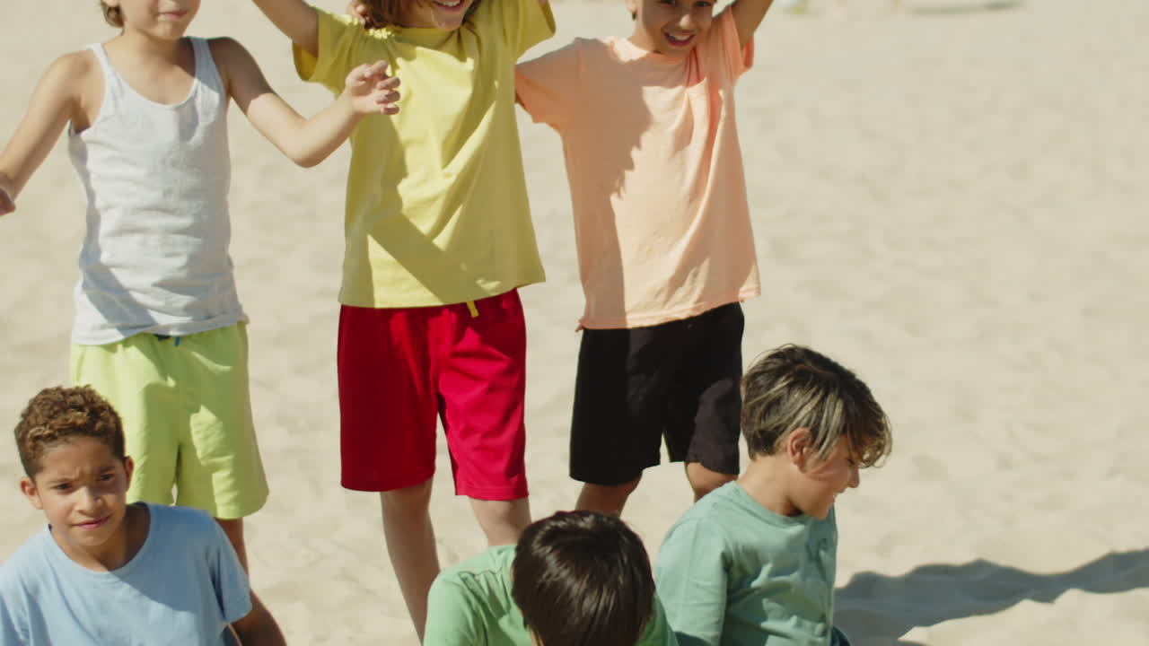 vista frontal del equipo de fútbol sentado en la playa y regocijándose