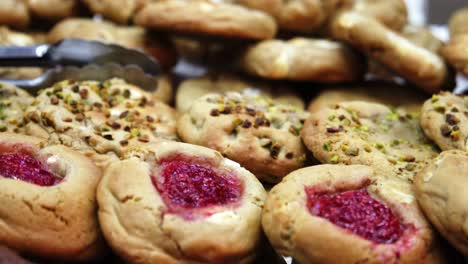 close up shot of cookies of different flavours at shop product table. chocolate, jam, nuts, pistachio, vanilla.