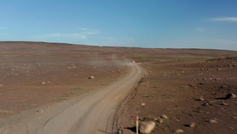 Drone-following-car-driving-in-rock-desert-in-isolated-volcanic-Iceland.-Birds-eye-4x4-vehicle-driving-off-road-exploring-icelandic-highlands