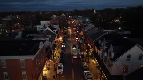 Aerial-drone-shot-of-traffic-and-people-in-small,-quaint-American-town-at-night
