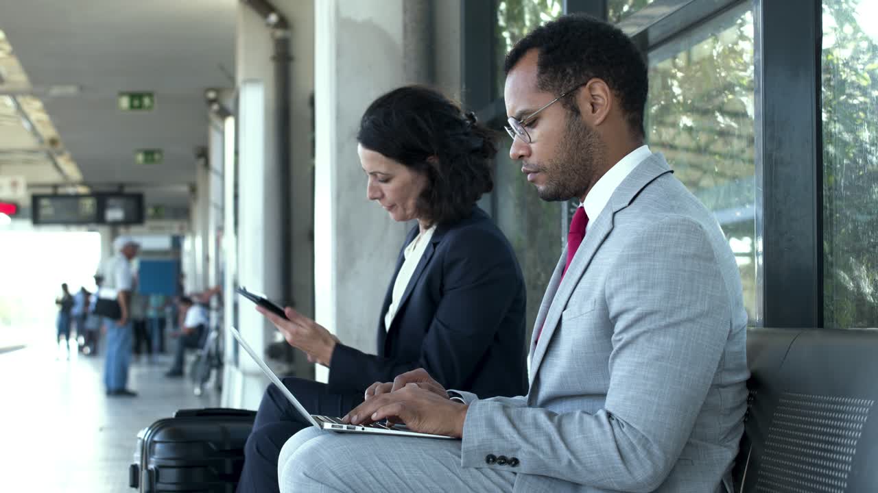 gente de negocios con aparatos en la estación de tren