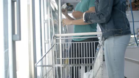 Cropped-shot-of-man-and-woman-taking-goods-from-fridge