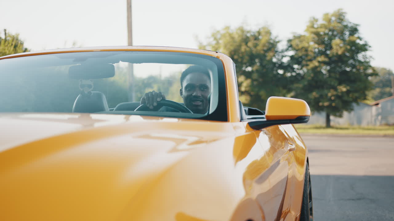 hombre conduciendo un coche descapotable amarillo