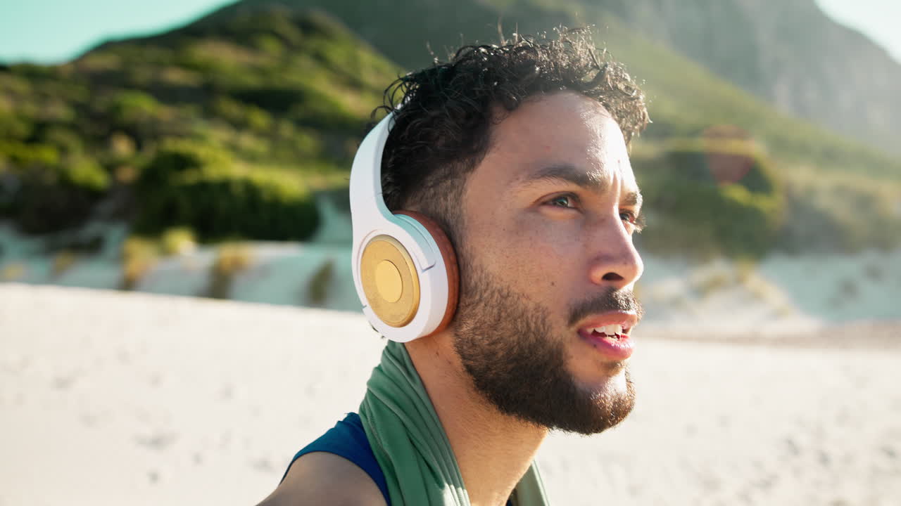 Giovane uomo in spiaggia che usa smartphone e cuffie