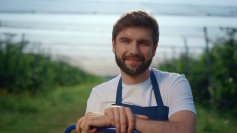 Young-agriculture-man-looking-camera-at-modern-sunny-outdoors-green-house.