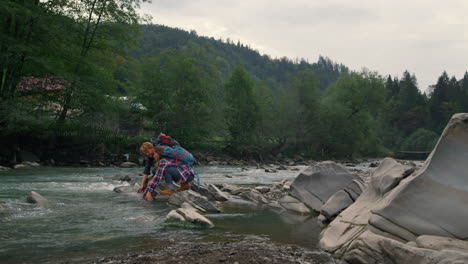 hikers touching water in river. positive couple splashing water with hands