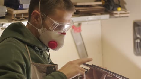 un carpintero está moliendo una pieza de madera, un producto de madera contrachapada hecho en una máquina láser cnc usando papel de arena