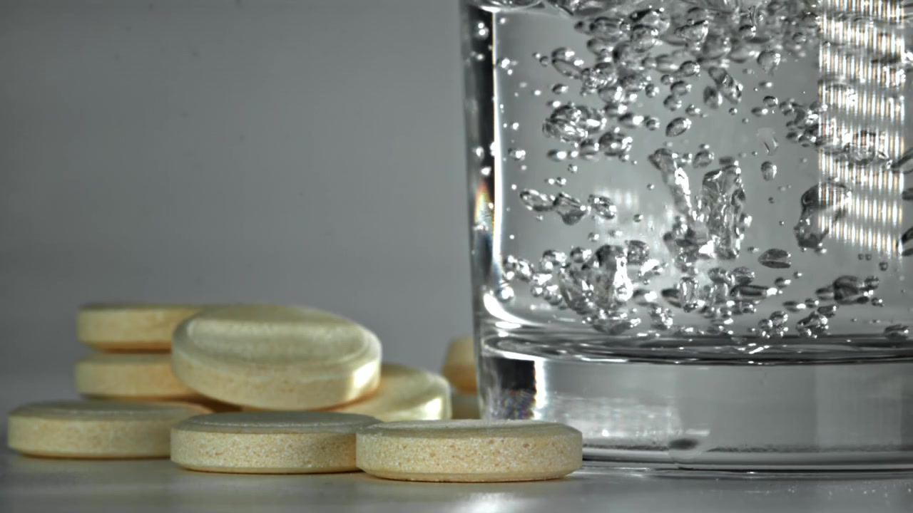 Compresse effervescenti accanto a un bicchiere d'acqua frizzante
