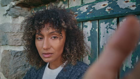 thoughtful woman looking camera in front wooden door closeup. curly model posing