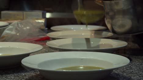 pouring soup on plates in kitchen