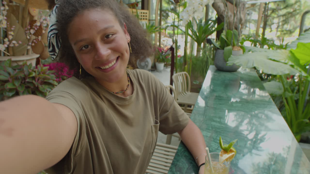 Girl Having Cocktail and Chatting on Camera in Outdoor Cafe