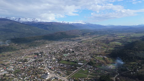 wide angle aerial shot of the city el bolson in argentina, snowy mountains in the background, copy space