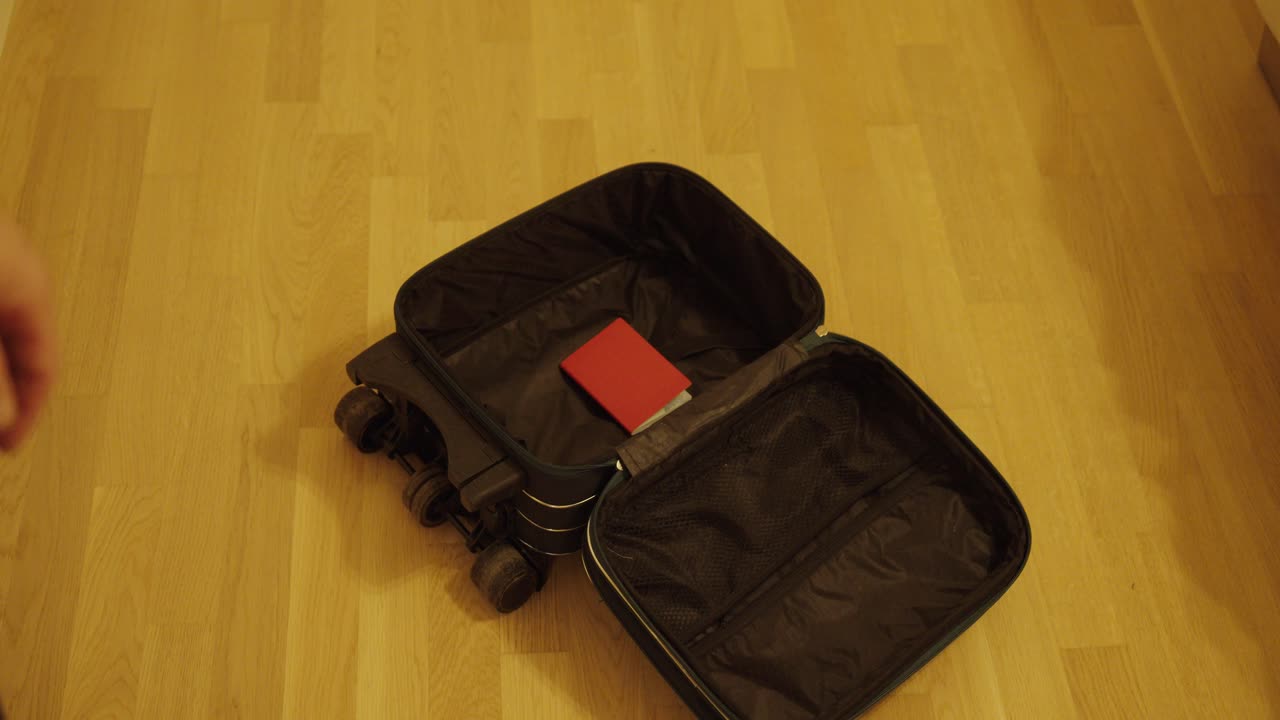 A person throws a red passport into an open suitcase before a trip, symbolizing preparation for travel, vacation, or an international journey