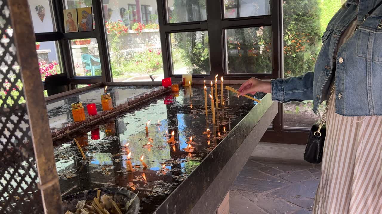 Believing woman placing candles in an Orthodox chapel in Romania. Close up