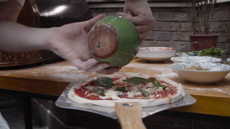 chef puts olive oil on to of neapolitan pizza dough