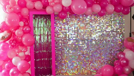 attaching pink balloons to a festive backdrop with shiny sequins