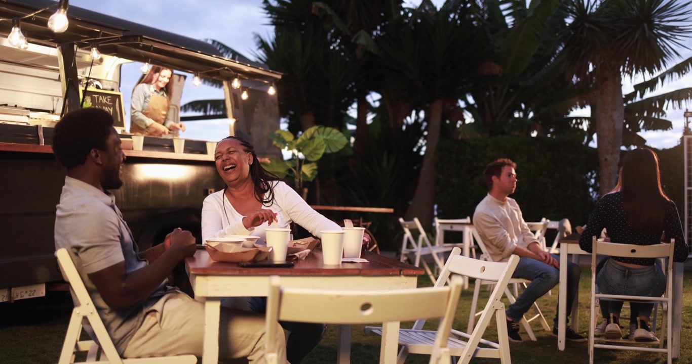 Happy Multiethnic Friends Laughing and Eating at Outdoor Food Truck