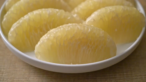 fresh peeled pomelo, grapefruit or shaddock on white plate