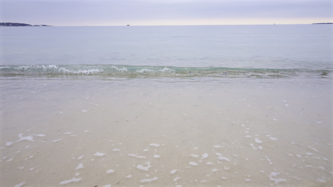 Waves of the Mediterranean crashing on the beach on a cloudy day at sunset