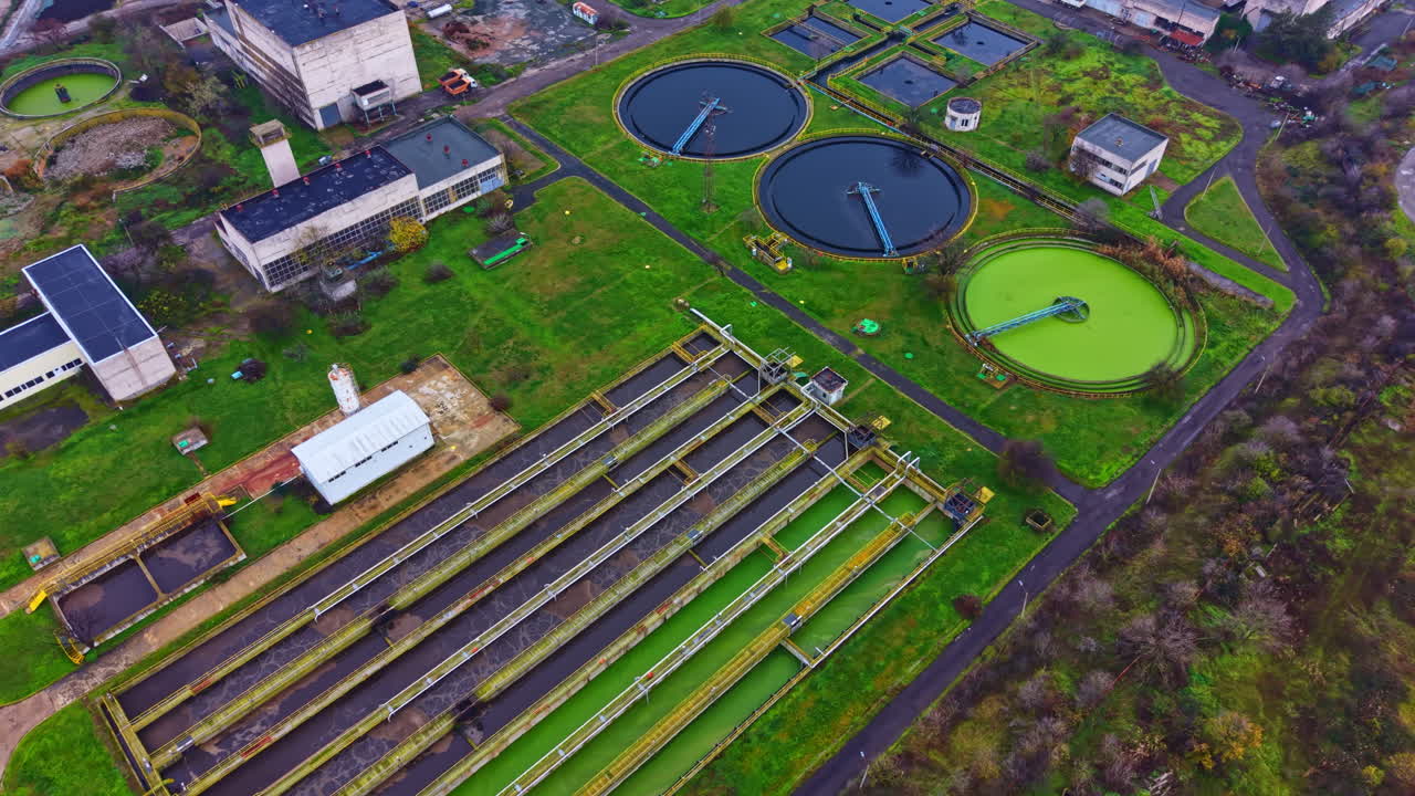 Water treatment facility showing multiple tanks and green facilities in an urban setting during daytime
