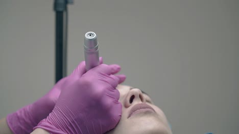 las manos del cosmetician del salón de belleza sostienen la frente del cliente lentamente.