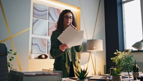 company director talking smartphone looking on work papers at modern workplace.
