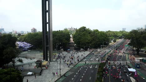 backwards quick drone shot of the city marathon runners as they pass the monument called light trail