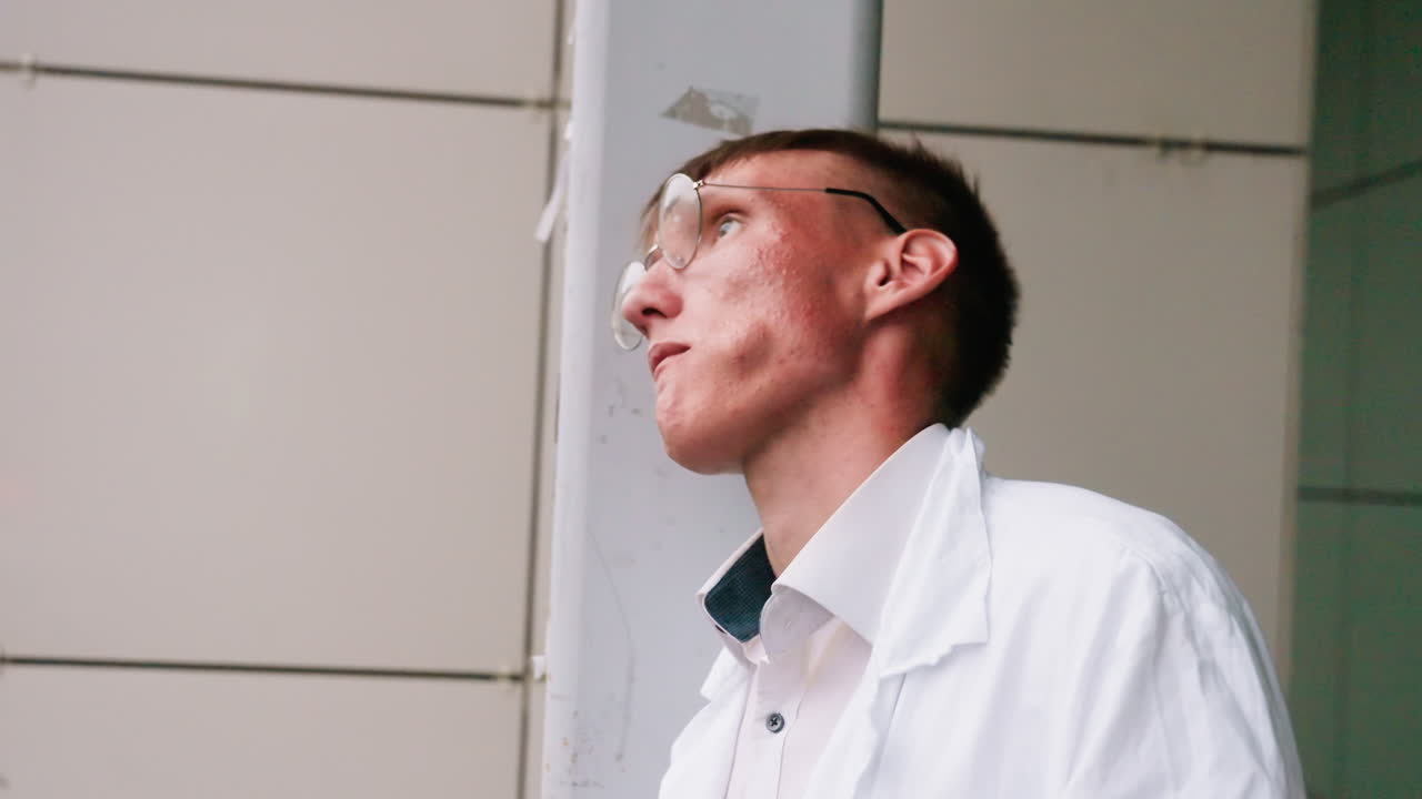 Scientific researcher in white coat standing on porch takes break eating pastry, calmly enjoying quick snack in urban environment with thoughtful posture and relaxed outdoor atmosphere