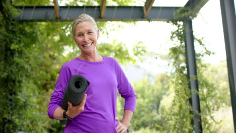 Senior-Caucasian-woman-holding-a-yoga-mat-outdoors