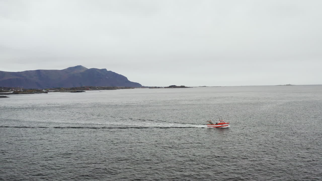 pequeño bote navegando por el océano atlántico en averoy, noruega en un día nublado