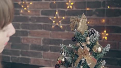 woman-adjusts-golden-bows-on-decorated-christmas-tree