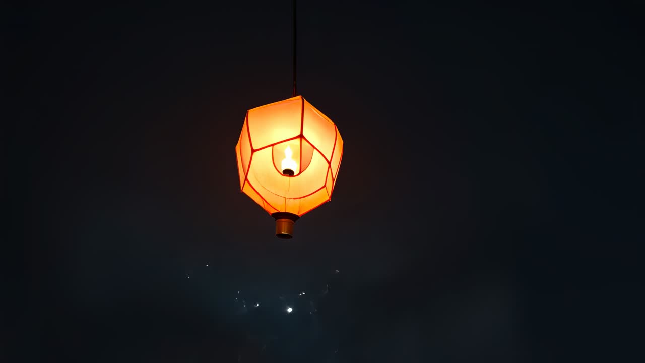 Growing orange faceted lantern glowing in night sky as inner light rises, thin cord with embers