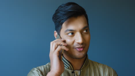 close-up view of indian young man in traditional clothes talking on the phone