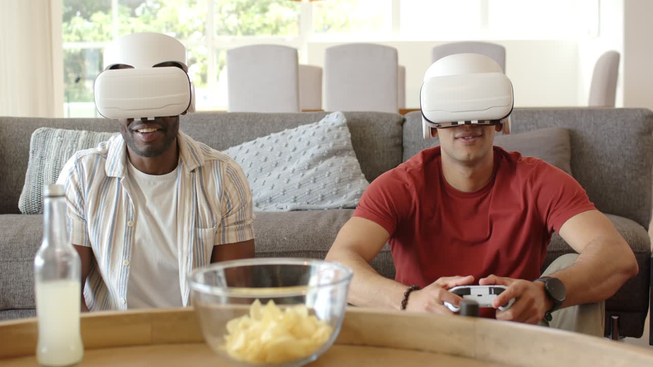 Uomini diversi che indossano visori VR e tengono in mano controller su un divano a casa, ridendo e giocando a un gioco VR